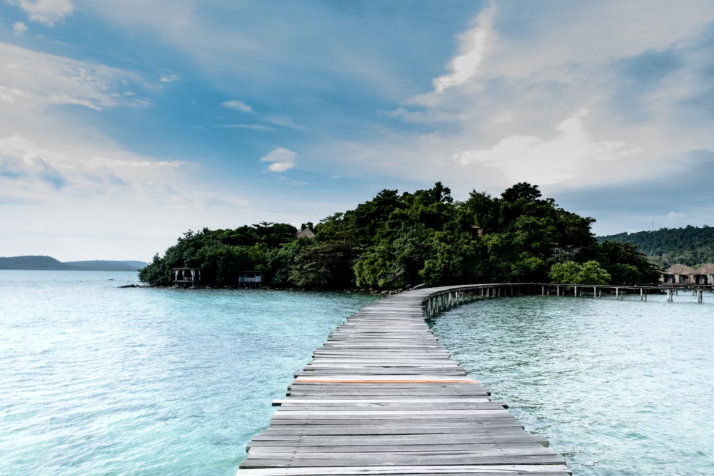 Wooden boardwalk over water leading to a tree-covered island
